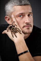 Portrait of a Young Handsome Man with Big Spider on His Hand. Happy and smiling