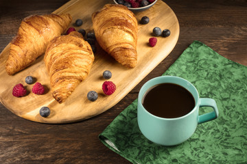 Cup of coffee with croissants and fresh berries