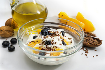 Healthy breakfast with quark or cottage cheese and linseed oil, fresh blueberries, orange, walnut and flax seeds, light gray background