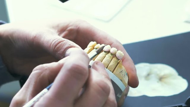 Dental technician applying ceramics glaze to a cast made with CNC dental machine