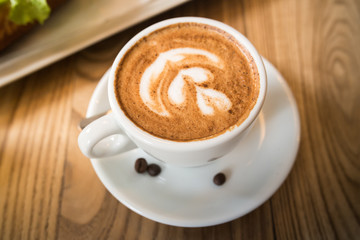 Cup of fresh espresso coffee with latte art on blright wooden table