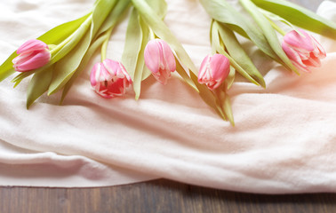 Pink tulips on white fabric, lit by the rays of the setting sun