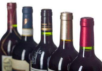 Row of wine bottles with dry red wine on white background. Low depth of field.