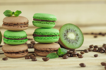 Green and brown french macarons with kiwi, coffee beans and mints decorations