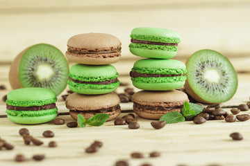 Green and brown french macarons with kiwi, coffee beans and mints decorations