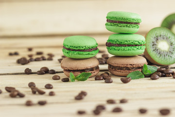 Obraz na płótnie Canvas Green and brown french macarons with kiwi, coffee beans and mints decorations