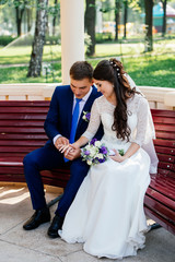 Naklejka premium The bride and groom sitting on a bench and holding hands