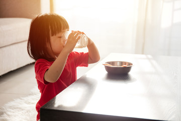 Asian Chinese little girl having breakfast with milk