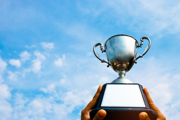 winner and champion concept, Hand holding championship trophy against blue sky