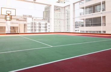 Tennis Court and bassketball hoop On rooftop of the hotel building with sunrise shadow