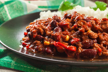 Hot chili con carne with ground beef, beans, tomatoes and corn served with rice