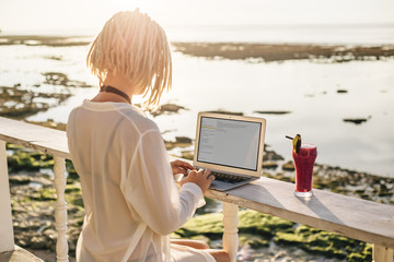 Woman working on laptop in beach bar