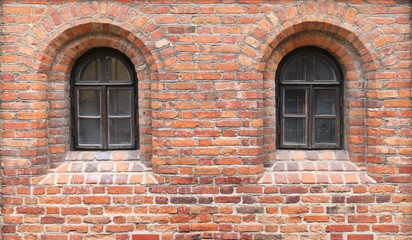 Fototapeta na wymiar In a red brick wall of the medieval castle there are two narrow windows