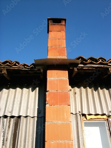 "Schornstein aus rotem Backstein einer Behausung aus Wellblech in