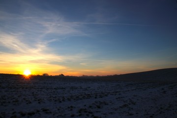 Hilly and snowy landscape at sunrise in February