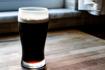 Dark Beer at kitchen on wooden surface.