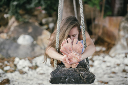 Woman practicing yoga on a swing at the beach