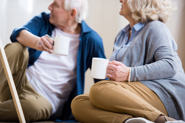 senior man and woman drinking coffee in art workshop