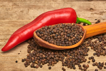 Closeup Red hot chili peppers and black pepper whole in wooden spoon on old wooden background
