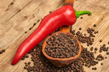 Closeup Red hot chili peppers and black pepper whole in wooden spoon on old wooden background