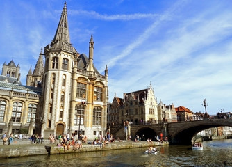 Fototapeta premium People chilling out at riverside In the afternoon of Sunday 18th May 2014, Ghent Historic Centre with Former Post Office and St Michael's Bridge, Belgium 