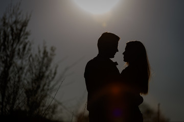 Man and woman hugging in the background of the setting sun. Silhouette.