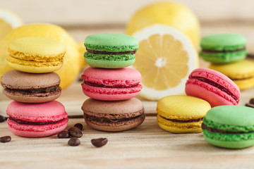 Fototapeta na wymiar Green, pink, yellow and brown french macarons with lemon and coffee beans