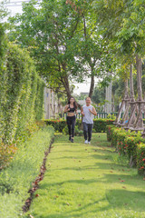Fototapeta na wymiar old man and woman exercise by jogging at the park, they are smiling and running on the grass outdoor. health concept