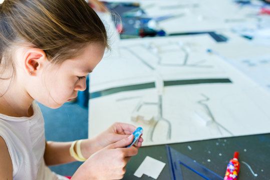 Young girl on the course of architectural design for children - preparing architectural model