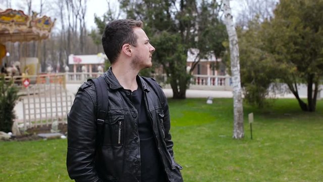 Portrait of a man in a park on the background of a carousel