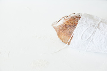 A loaf of homemade bread in a paper on a white background with space for your text.