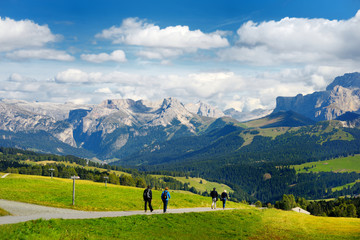 Tourists hiking in Seiser Alm, the largest high altitude Alpine meadow in Europe, stunning rocky...