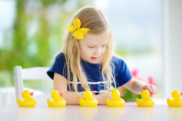 Cute little girl playing with rubber ducklings at home © MNStudio