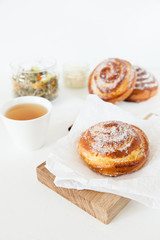 Obraz na płótnie Canvas Herbal tea and sweet buns with sugar and cinnamon on a white background.