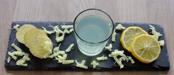 Tray with ginger drink, slices of ginger and lemon and grated ginger