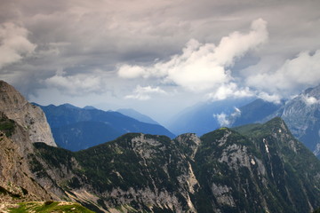 Fototapeta premium The misty Trenta Valley covered with storm clouds with the forested ridge of Velika Ticarica from Triglav Lakes Valley (Julian Alps, Triglav National Park, Slovenia).