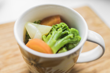 Fresh carrots, broccoli, potatoes, onions in a cup.