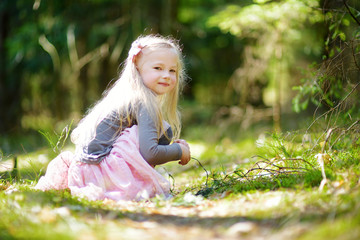 Adorable little girl picking the first flowers of spring in the woods on beautiful sunny spring day