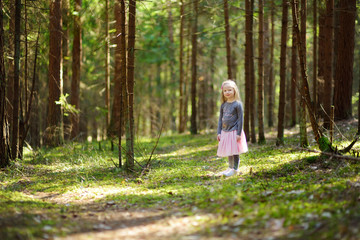 Naklejka na ściany i meble Cute little girl having fun during forest hike on beautiful spring day.