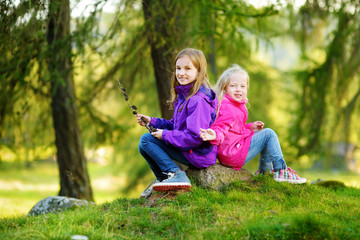 Two funny little sisters having fun during forest hike on beautiful autumn day in Italian Alps
