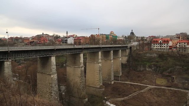 Novoplanovskiy bridge in Kamianets-Podilskyi city, located in historic region of Podolia, western Ukraine. Cars and people on stone bridge above Smotrych river in Kamianets-Podilskyi city,length 136 m