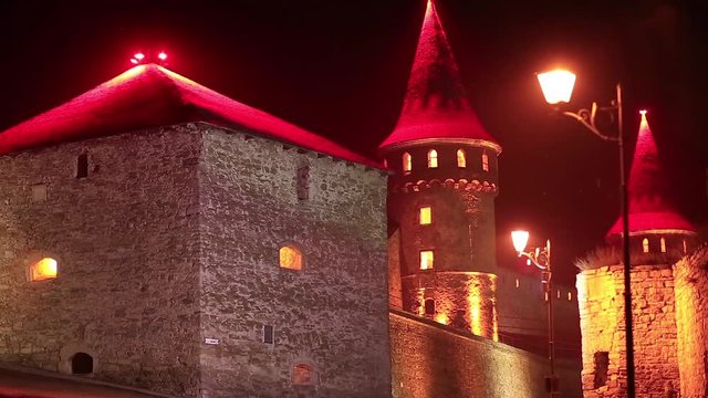 Old castle with red illumination at night, is former Ruthenian-Lithuanian castle and a later Polish fortress, located in historic city of Kamianets-Podilskyi, in historic region of Podolia in Ukraine