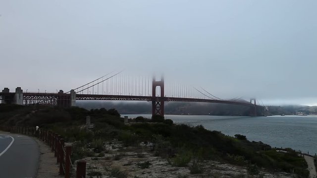 Foggy Golden Gate Bridge with grass as foreground from south shore. Symbol, icon and landmark of San Francisco, California, United States. Fog in summer. American travel concept.
