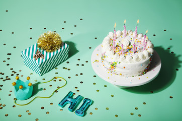 Birthday cake with lit candles and sprinkles, assorted props 