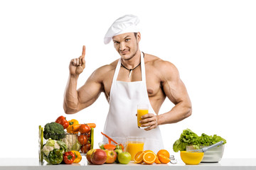 Man bodybuilder cook, cooking freshly squeezed juice and vegetables salad