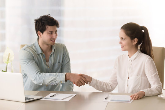 Smiling businessman handshaking with young businesswoman before office meeting or discussion, starting teamwork on project, interesting acquaintance, beginning of the course