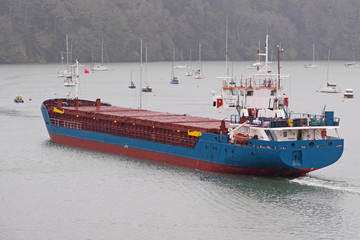 Cargo ship making its way in heavy rain up the Truro river near Malpas guided by a pilot boat en route to the river Fal © pjhpix