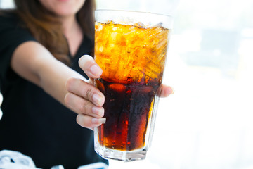 Woman hand giving glass of cola.Glass of cola ,Soft drinks with ice.