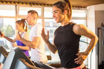 Smiling sporty woman running on a treadmill in gym.