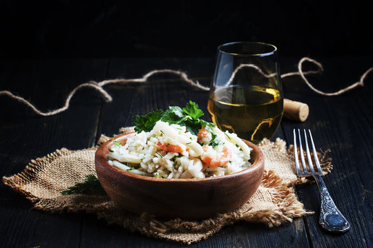 Risotto with shrimp and squid in a wooden bowl, dark background, selective focus